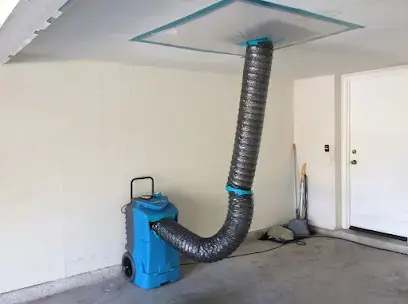 Dehumidifier feeding dry air through a duct into an opened ceiling in a Laguna Niguel room