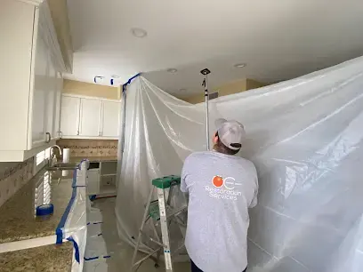 Technician hanging plastic containment sheeting from a ceiling during a water damage dry-out