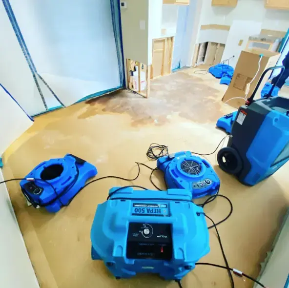 Air movers, a dehumidifier and a HEPA air scrubber running on a bare subfloor during a Laguna Niguel dry-out