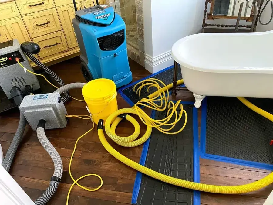 Dehumidifier, floor drying mats and hoses set beside a clawfoot tub during a Laguna Niguel bathroom leak dry-out