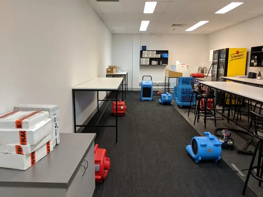 Air movers and dehumidifiers drying carpet in an office break room, commercial water damage in Laguna Niguel