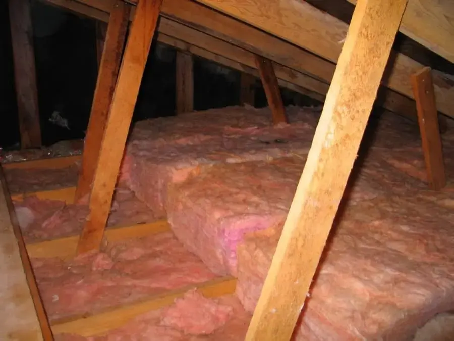 Attic rafters and pink insulation under a leaking roof, roof leak water damage in Laguna Niguel
