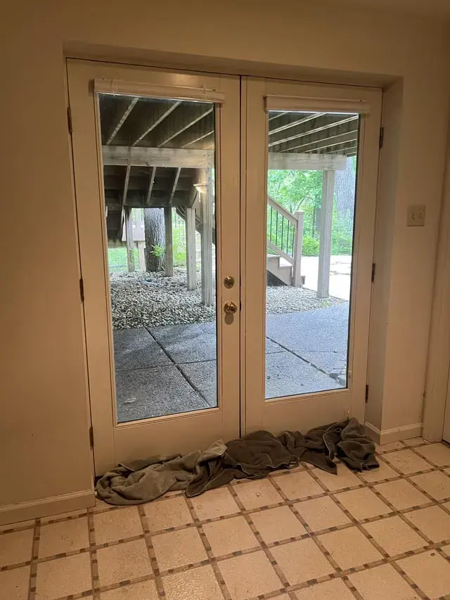 Wet towels piled at French patio doors after storm water came inside, Laguna Niguel storm water damage
